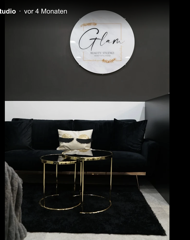 Glam Beauty Studio Logo-Schild über schwarzem Samtsofa mit goldenen Beistelltischen